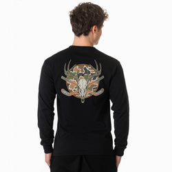A man viewed from the back wearing a black long-sleeve shirt with a large graphic on the back featuring a deer skull with antlers, crossed hockey sticks, and a camouflage circle.