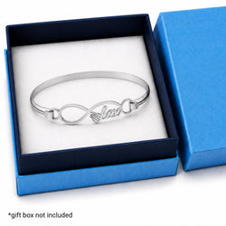 A silver infinity bracelet with a small lax stick and the word 'lax' on the side, displayed inside an open blue gift box with a white insert. Text at the bottom left reads '*gift box not included'.