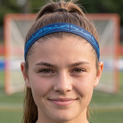 Person wearing a blue headband with lacrosse stick designs on a blurred sports field background