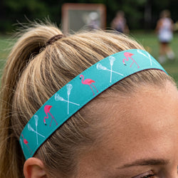 Person wearing a turquoise headband with flamingo and lacrosse stick designs outdoors.