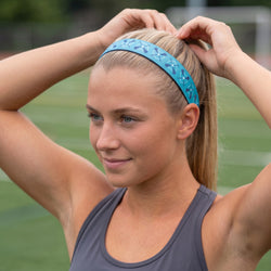 Woman adjusting a blue lacrosse headband on a sports field