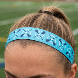 Person wearing a blue headband with lacrosse designs on a blurred green background