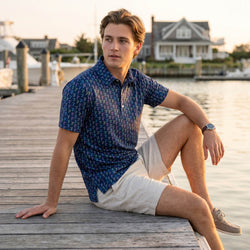 Teen wearing a hockey patterned polo shirt outdoors by a pier.