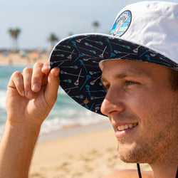 Man holding a bucket hat with a beach background