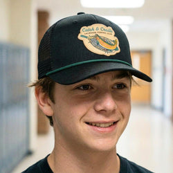 Person wearing a black cap with a lacrosse fish logo in an indoor setting