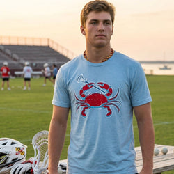 Teenage boy wearing a blue t-shirt with a red crab design on a sports field.
