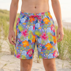 Colorful tropical patterned lacrosse swim trunks on a beach setting