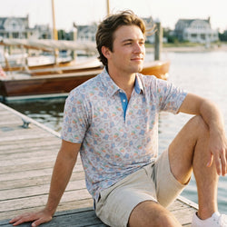 Person wearing a lacrosse patterned polo shirt on a pier.
