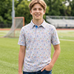 Person wearing a lacrosse patterned polo shirt on a field.