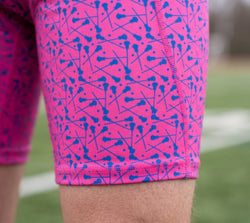 Close-up of pink shorts with blue lacrosse pattern on a grassy background