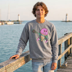 Person wearing a gray sweatshirt with a colorful ice cream cone and stick graphic, standing on a wooden dock by the water.