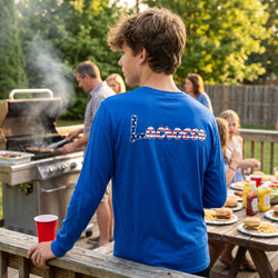 Person wearing a blue 'Lacrosse' shirt at a outdoor gathering with food and drinks.