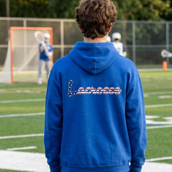 Person wearing a blue hoodie with 'Lacrosse' on the back, standing on a lacrosse field.