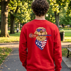 Person wearing a red sweatshirt with a graphic of a dog holding a lacrosse stick and American flag bandana in a park.