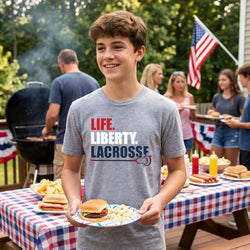 Person wearing a 'Life. Liberty. Lacrosse' t-shirt at a casual outdoor gathering.
