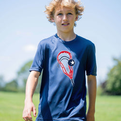 Young boy wearing a blue t-shirt with a lacrosse stick design outdoors.