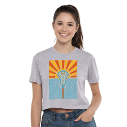 Woman wearing a gray t-shirt with a colorful sunset lacrosse graphic design on a white background