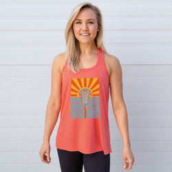 Woman wearing a coral tank top with a sunset lacrosse graphic design against a light gray background