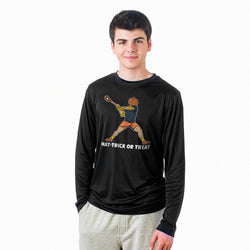 A young man wearing a black long-sleeve performance shirt with a graphic of a lacrosse player with a pumpkin head and the text 'HAT-TRICK OR TREAT' on the front, paired with light gray sweatpants, against a plain white background.