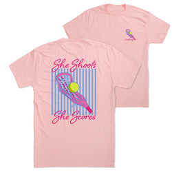 A light pink short-sleeve t-shirt shown from both the front and back. The front features a small pink and blue lacrosse logo on the left chest with the text 'She Shoots She Scores'.
