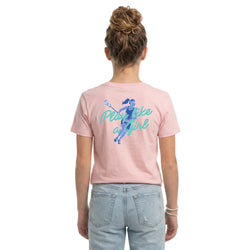 A woman viewed from behind wearing a light pink short-sleeve t-shirt with a blue graphic of a volleyball player and the text 'Play like a girl' on the back, paired with light-wash blue jeans against a plain white background.