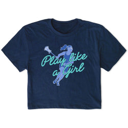 A navy blue short-sleeve crop top t-shirt featuring a graphic of a female lacrosse player in blue and white, with the text 'Play like a Girl' written in light blue cursive across the front.