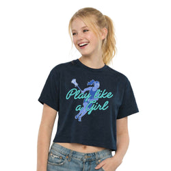 A smiling young woman wearing a cropped navy graphic T-shirt with a blue cheerleader illustration and the text 'Play like a Girl' in teal, paired with light-wash jeans, against a plain white background.