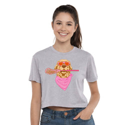 A smiling young woman wearing a light heather gray cropped T-shirt with a colorful graphic of a golden retriever wearing orange sunglasses, a pink bandana, and holding a pink lacrosse stick. She is also wearing blue jeans against a plain white studio background.