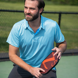 Person wearing Light blue pickleball polo shirt featuring a repeating yellow and teal paddle pattern.