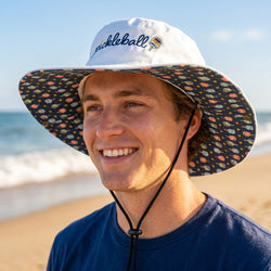 Person wearing a colorful bucket hat with 'Pickleball' text on a beach