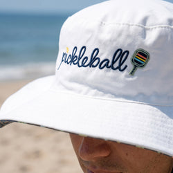 White bucket hatt with 'pickleball' embroidery on a beach
