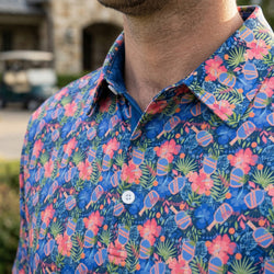 Close-up of a colorful floral pickleball patterned polo shirt with a blurred outdoor background
