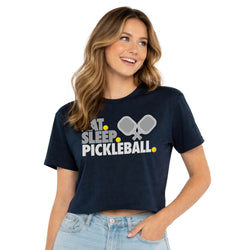 Woman wearing a navy blue t-shirt with 'Eat. Sleep. Pickleball.' text and pickleball paddle graphics.