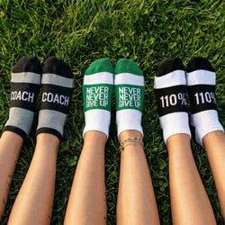Models wearing ankle socks with motivational messages sitting on the grass