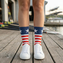 Person wearing red, white, and blue striped socks on a wooden dock.