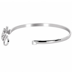 A polished silver-tone metal cuff bracelet with a small dangling script charm on one end, shown on a plain white background.