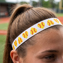 Person wearing a headband with yellow softball icons on a blurred sports field background