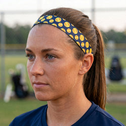 Woman wearing a blue headband with yellow softball patterns on a sports field.