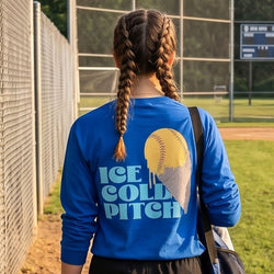 Person wearing a blue long sleeve shirt with a softball design and 'Ice Cold Pitch' text on a baseball field.