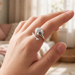 Hand of a girl wearing a silver soccer themed ring with gem stones.