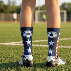Person wearing socks with soccer ball designs on a grassy field