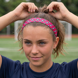 Person wearing a pink headband with soccer ball pattern on a sports field