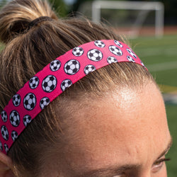 Person wearing a pink headband with soccer ball pattern on a sports field