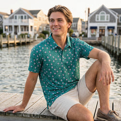 Teen sitting on a dock by a waterfront wearing a soccer polo shirt with houses in the background