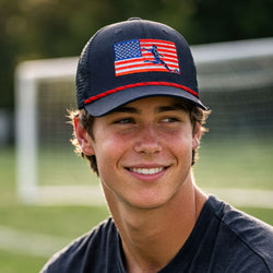 Person wearing a cap with an American flag soccer design on a sports field