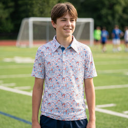 Person wearing a patriotic themed polo shirt with soccer patterned design on a field.