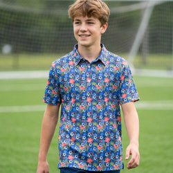Young boy wearing a colorful soccer patterned polo shirt on a grassy field.