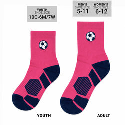 A pair of pink and navy blue crew socks with soccer-themed design details, including a soccer ball graphic on the cuff and a soccer-ball-inspired pattern on the sole, shown on a plain white background.