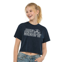Young girl wearing a navy blue t-shirt with 'Just Kickin' It' text on a white background