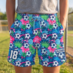 Colorful shorts with soccer ball and floral pattern worn by a person on a grassy field.